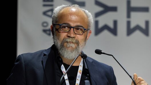 «Σαν να μην πέρασε μια μέρα. Μόνο λίγο χειρότερα...» 36 Άνδρας με γκρίζα γενειάδα και γυαλιά μιλάει σε μικρόφωνο σε εκδήλω…