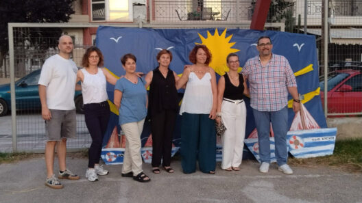 Η καλοκαιρινή γιορτή του ΚΔΑΠ Αρκτικού Διαμερίσματος ΦΩΤΟ 36 Επτά ενήλικες ποζάρουν μπροστά σε ένα μπλε καλοκαιρινό πανό με ήλι…
