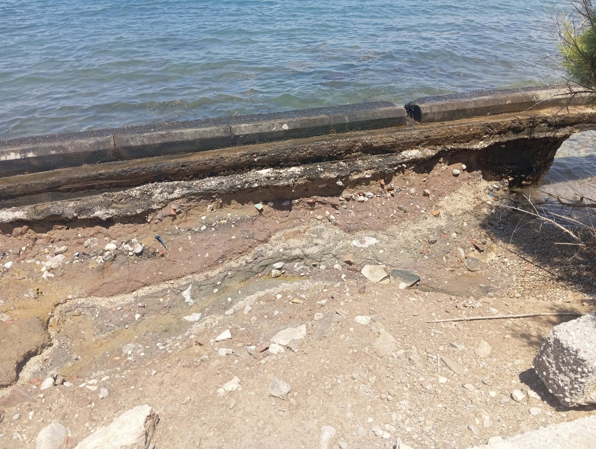 Κατεστραμμένο τσιμεντένιο τοιχίο δίπλα στη θάλασσα με εμφανή διάβ…