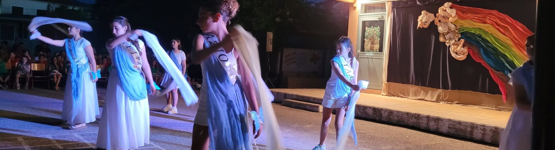 Μαθήτριες χορεύουν με λευκά ρούχα και υφάσματα σε σχολική γιορτή λ…