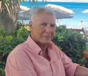 Άνδρας με γκρίζα μαλλιά και ροζ ριγέ πουκάμισο χαμογελά σε εξωτερι…