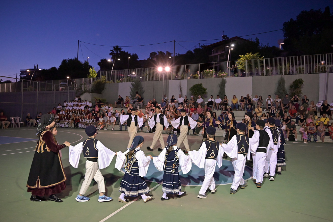 Παιδιά και έφηβοι με παραδοσιακές ελληνικές ενδυμασίες χορεύουν σ…