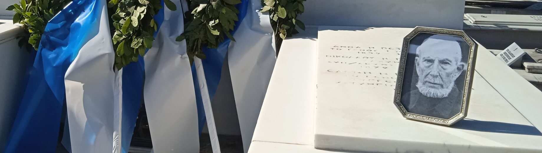 Τάφος με στεφάνι δάφνης, ελληνικές σημαίες και φωτογραφία του Ηρακ…