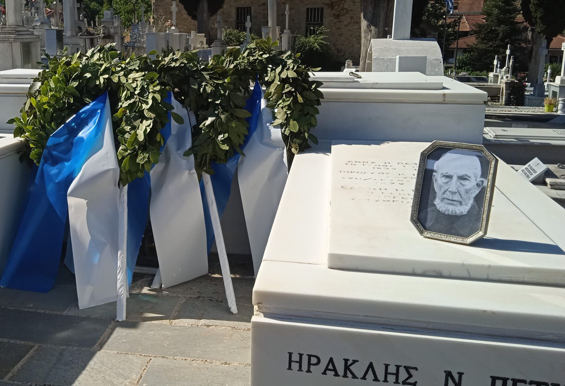 Τάφος με στεφάνι δάφνης, ελληνικές σημαίες και φωτογραφία του Ηρακ…