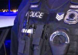 Κοντινό πλάνο αστυνομικού γιλέκου με τη λέξη «POLICE», χειροπέδες και…