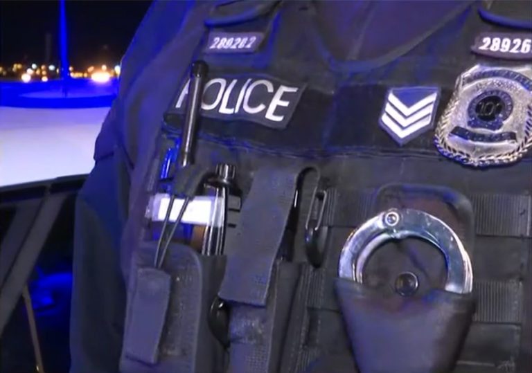 Κοντινό πλάνο αστυνομικού γιλέκου με τη λέξη «POLICE», χειροπέδες και…