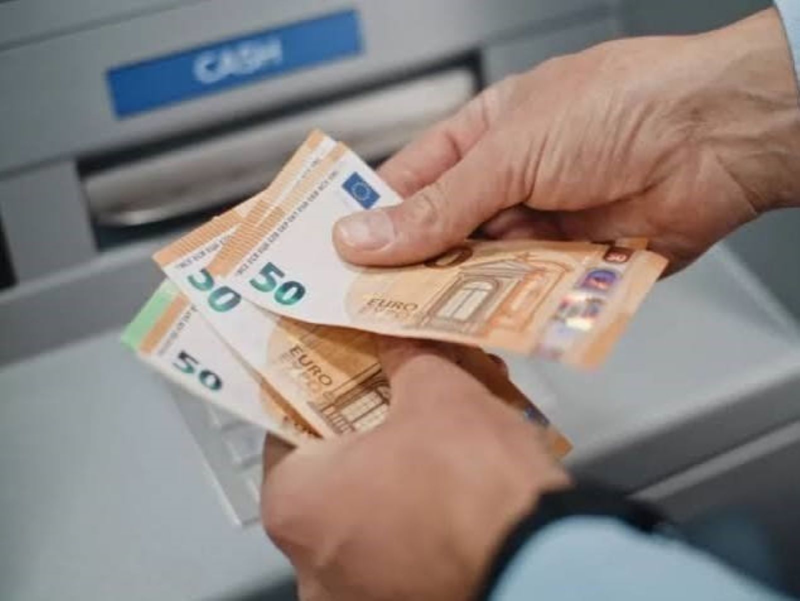 Κοινοί τραπεζικοί λογαριασμοί: Πότε η μεταφορά χρημάτων γίνεται φορολογική παγίδα 4 Χέρια κρατούν χαρτονομίσματα 50 ευρώ μπροστά σε ΑΤΜ.