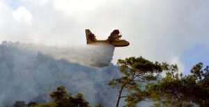 Κίτρινο πυροσβεστικό αεροσκάφος Canadair ρίχνει νερό σε δασική πυρκαγ…