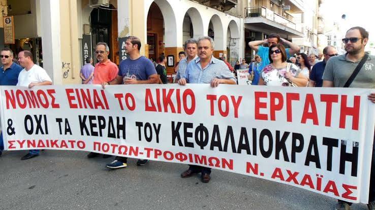 Διαδηλωτές κρατούν πανό με σύνθημα υπέρ των εργατών, στην Αχαΐα.