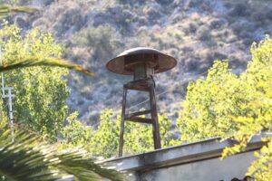 Σειρήνα συναγερμού σε μεταλλική βάση σε ταράτσα με πράσινο φόντο.