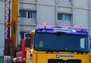 Κίτρινο γερανοφόρο όχημα με λογότυπο ΧΡΥΣΑΝΘΟΠΟΥΛΟΣ μπροστά σε κτ…