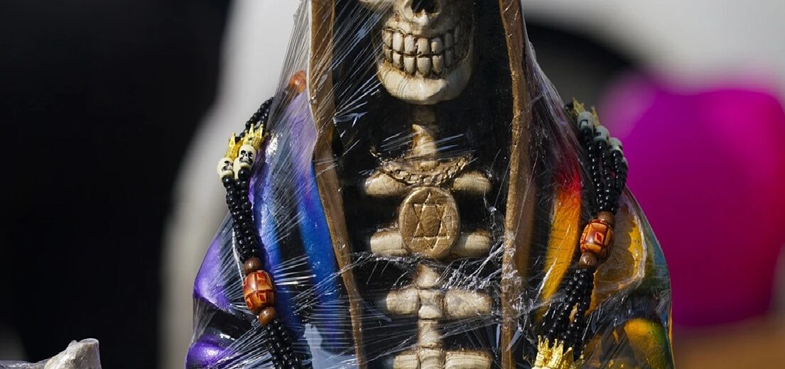 Κοντινό πλάνο αγάλματος σκελετού Santa Muerte τυλιγμένου σε πλαστικό, διακοσμημένο με μενταγιόν Άστρο του Δαβίδ και χάντρε…