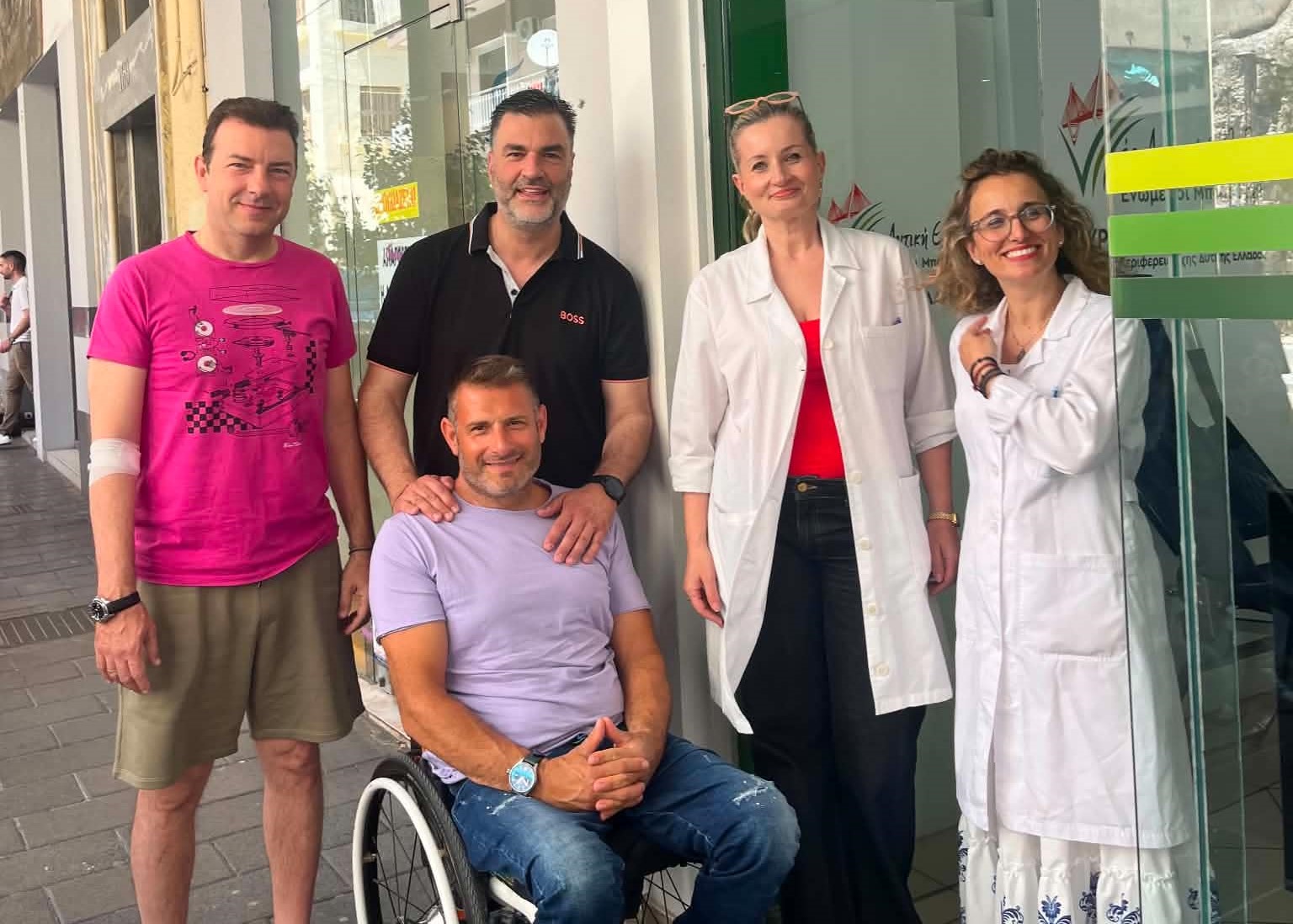 Πέντε άτομα, δύο με ιατρικές ποδιές, ένας σε αναπηρικό αμαξίδιο, σε …