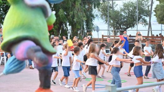 Γιορτή λήξης της Κατασκηνωτικής περιόδου στο Πάρκο Εκπαιδευτικών Δράσεων και στα Ροΐτικα ΦΩΤΟ 12 Παιδιά με λευκά μπλουζάκια χορεύουν χέρι-χέρι σε κύκλο σε εξωτερικ…