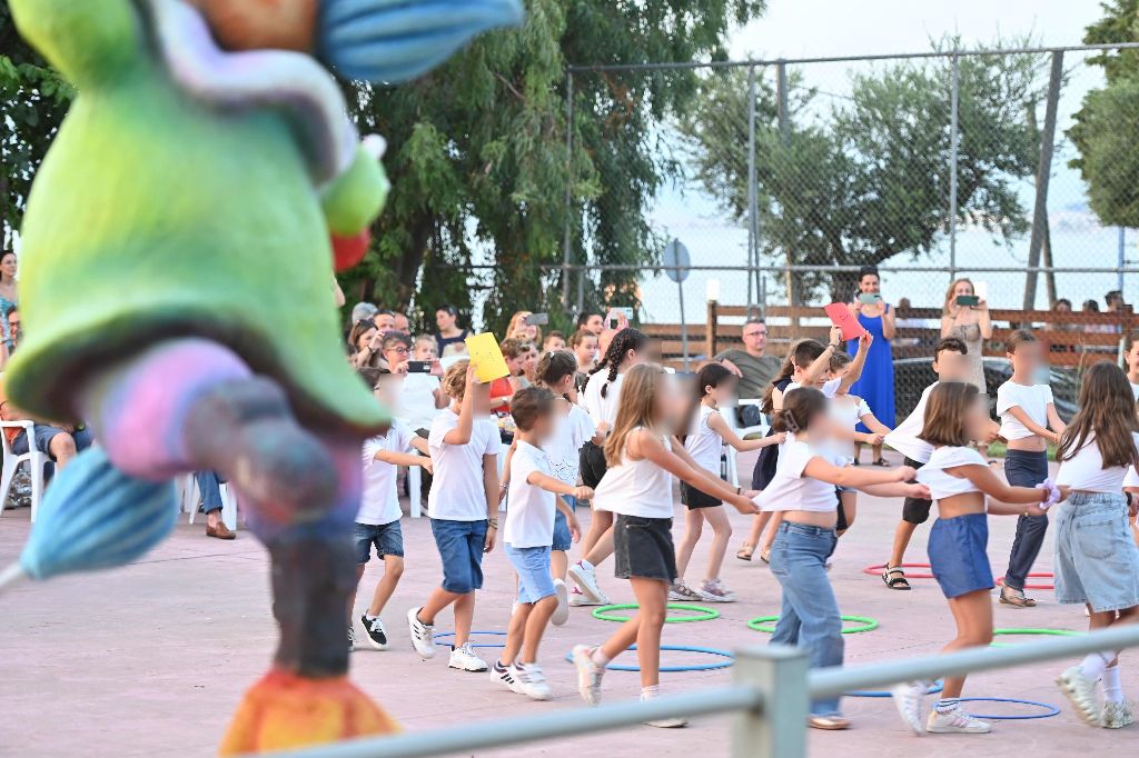 Παιδιά με λευκά μπλουζάκια χορεύουν χέρι-χέρι σε κύκλο σε εξωτερικ…