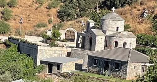 Πέτρινη εκκλησία με τρούλο και σταυρό, περιτριγυρισμένη από άλλα π…