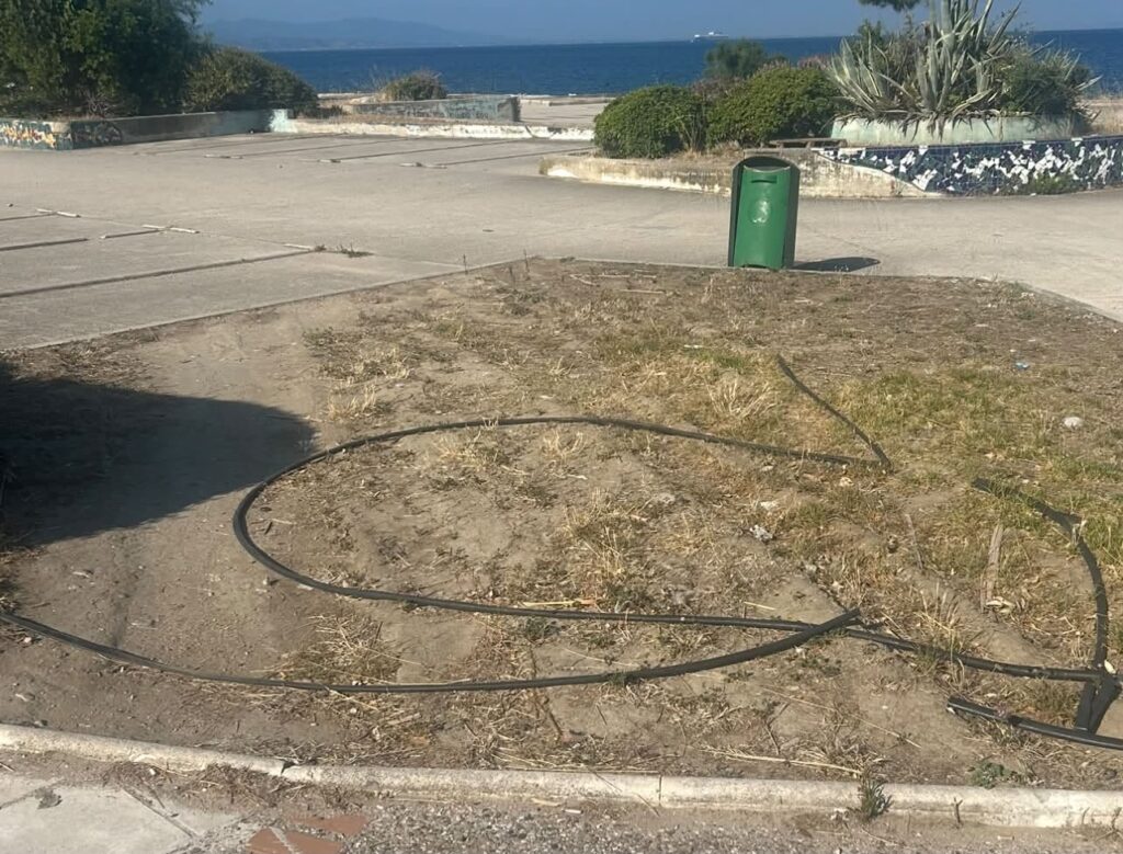 Ξηρό χωμάτινο έδαφος με σωλήνες άρδευσης δίπλα σε πάρκινγκ και θάλ…