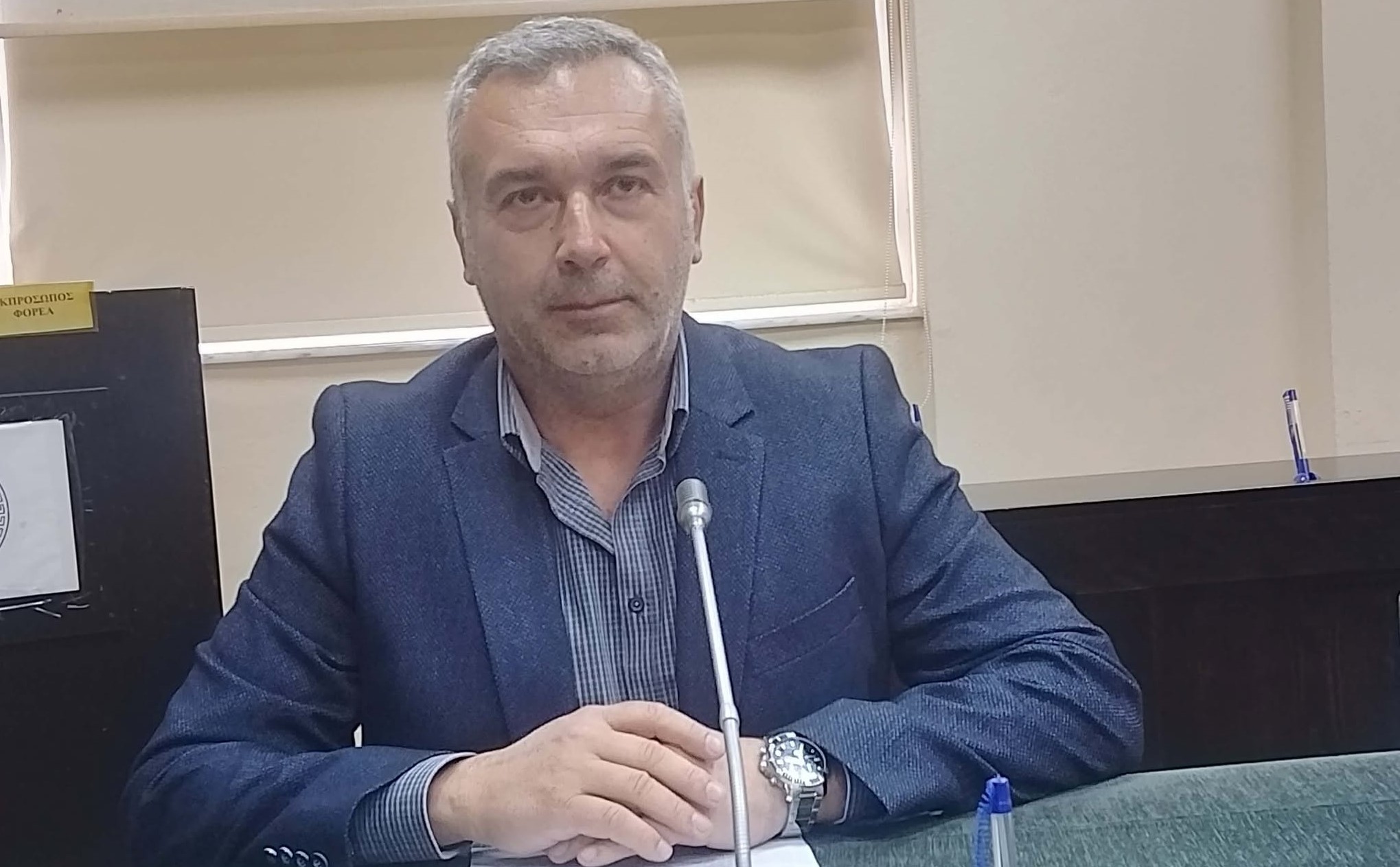 Άνδρας εκπρόσωπος φορέα με μπλε σακάκι και ριγέ πουκάμισο μιλάει σ…
