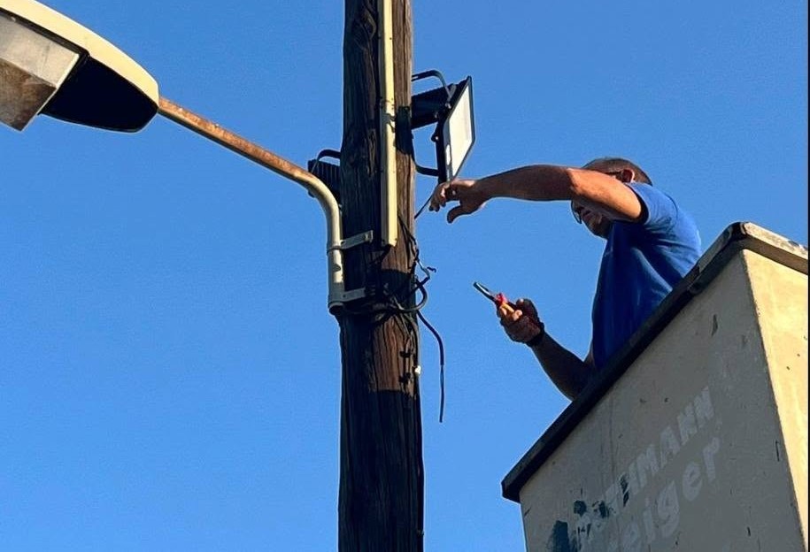Τεχνικός εγκαθιστά φώτα σε στύλο στην πλατεία παραλίας του Κάτω Αλ…