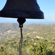 Καμπάνα εκκλησίας με θέα σε καταπράσινα βουνά, ένα χωριό και τη θάλ…