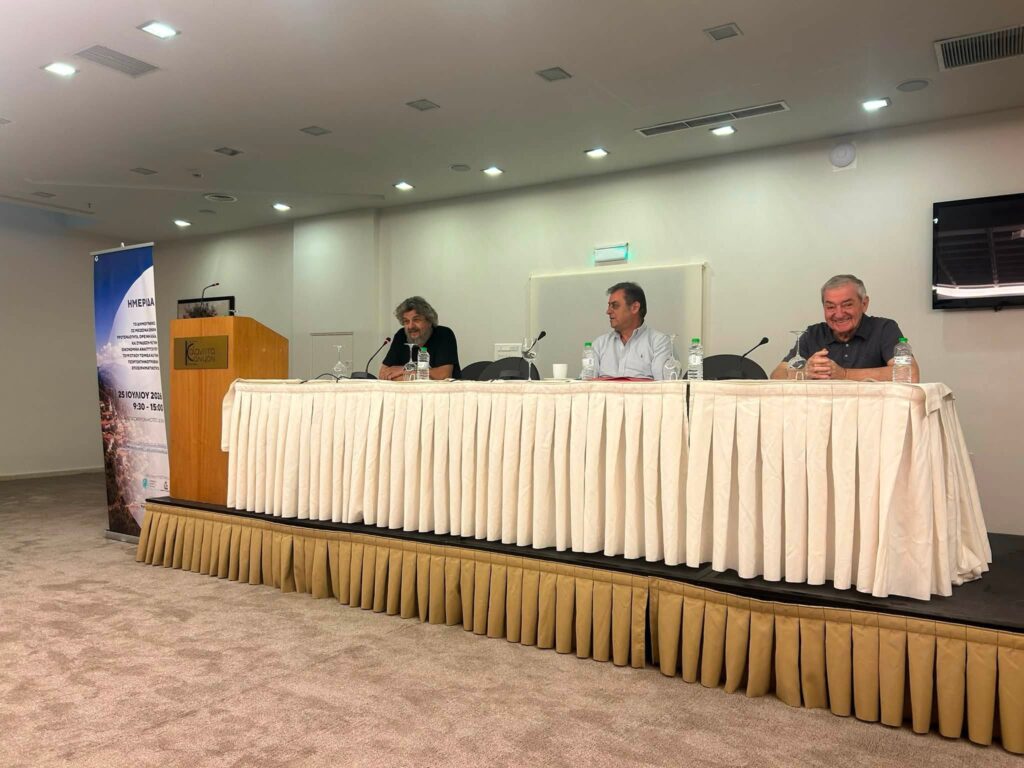 Τρεις άνδρες σε τραπέζι συνεδρίου στα Καλάβρυτα.