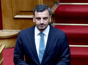 Ο Κώστας Σκρέκας με σκούρο κοστούμι και γαλάζια γραβάτα σε επίσημο…