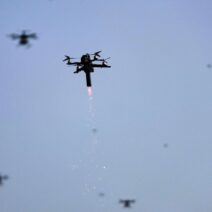 Ένα drone εκτοξεύει φλόγες και σπίθες στον ουρανό, με άλλα drones στο βάθ…
