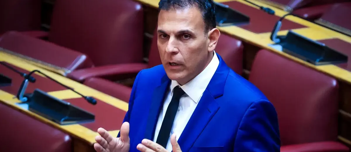 Ο Γιώργος Καραμέρος με μπλε κοστούμι μιλάει και χειρονομεί σε συνε…