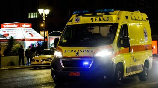 Ασθενοφόρο του ΕΚΑΒ με αναμμένους φάρους τη νύχτα, σε δρόμο πόλης.