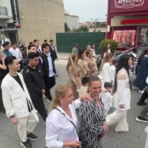 Πλήθος ανθρώπων περπατά σε αστικό δρόμο με καταστήματα, πιθανόν σε…