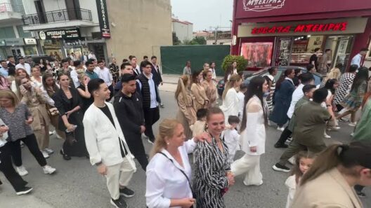 Πλήθος ανθρώπων περπατά σε αστικό δρόμο με καταστήματα, πιθανόν σε…
