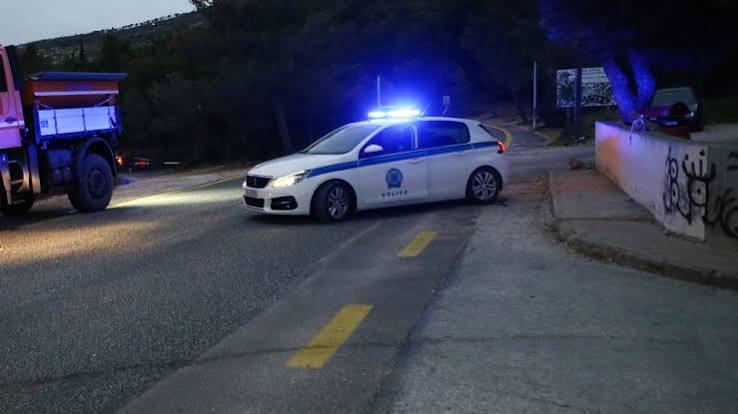 Αστυνομικό όχημα με αναμμένους φάρους σε δρόμο, με ένα φορτηγό στο …