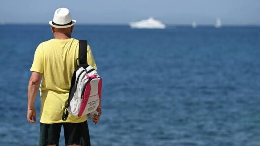 Άνδρας με καπέλο και σακίδιο κοιτάζει τη θάλασσα, με ένα μεγάλο γιο…