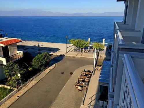 Παραλιακός δρόμος με τραπέζια, κτίρια και βλάστηση δίπλα στη γαλάζ…