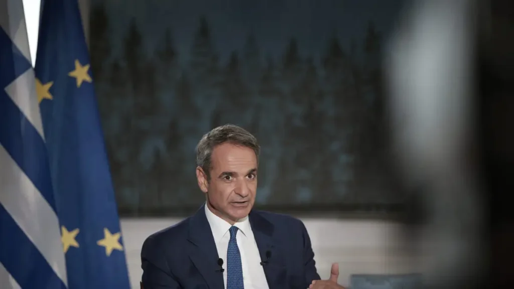 Ο Κυριάκος Μητσοτάκης μιλάει, με τις σημαίες της Ελλάδας και της Ευ…