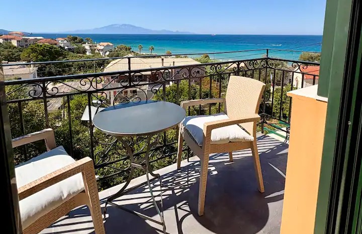 Μπαλκόνι με τραπέζι και καρέκλες με θέα σε μια ηλιόλουστη παραθαλά…