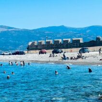 Άνθρωποι κολυμπούν και χαλαρώνουν σε παραλία στο Ρίο, με βότσαλα, π…