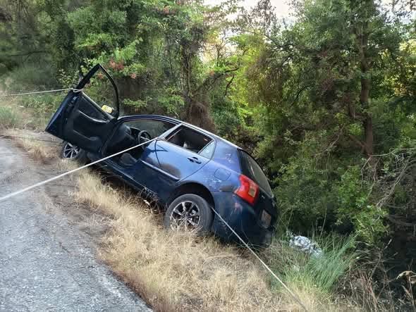 Μπλε αυτοκίνητο κρέμεται με σχοινιά στην άκρη ενός χωματόδρομου, έ…