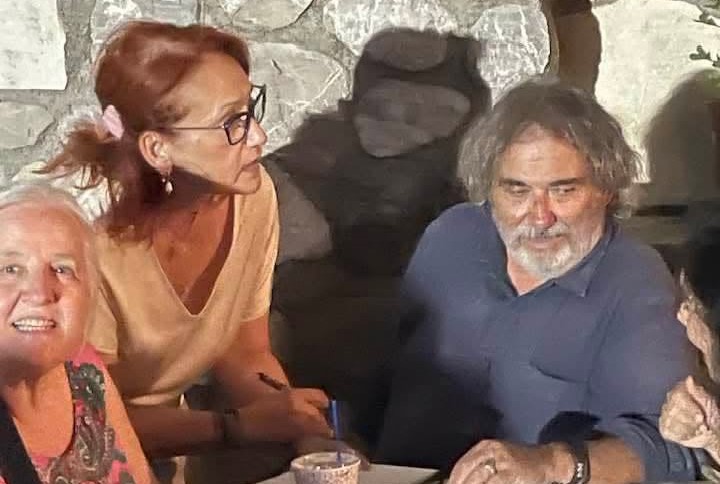 Γυναίκα με γυαλιά κρατάει στυλό, ενώ ένας άνδρας με γένια κοιτάζει …