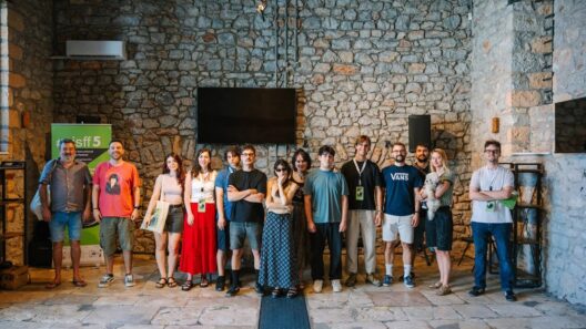 AISFF5 | «Φωτίζοντας τον διάλογο» στο Αίγιο 34 Ομάδα ανθρώπων και ένα σκυλάκι ποζάρουν μπροστά σε πέτρινο τοίχο σ…