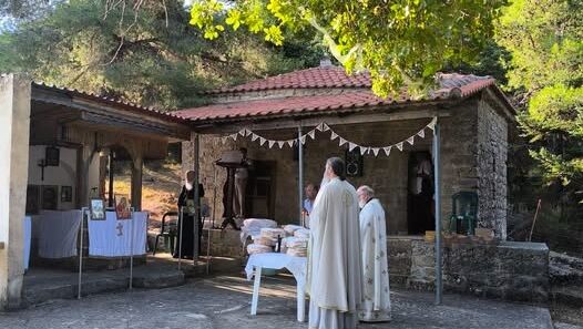 Ιερείς τελούν λειτουργία σε εξωκλήσι, με άρτους ευλογίας σε τραπέζι.