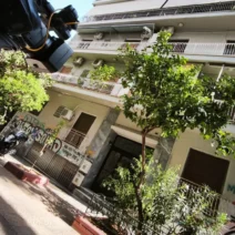 Κάμερα σε τρίποδο μπροστά σε πολυκατοικία στην Κυψέλη, με γκράφιτι…