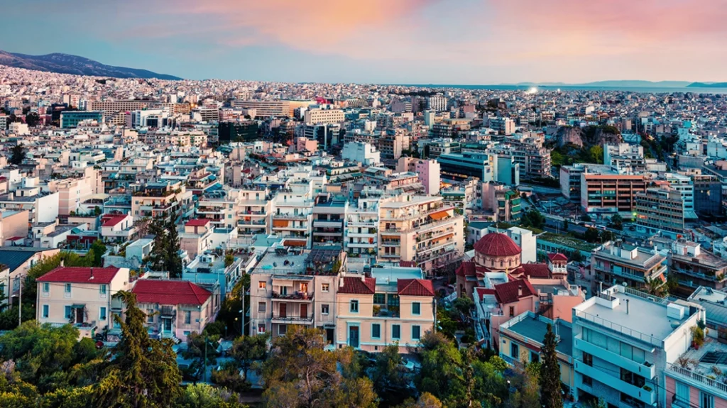 Πανοραμική θέα της Αθήνας με πλήθος κτιρίων, βουνά στο βάθος και ρο…