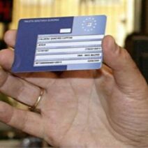 Ένα χέρι κρατά μια Ευρωπαϊκή Κάρτα Υγείας, σχετική με απάτη μέσω email.