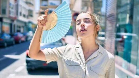 Νεαρή γυναίκα δροσίζεται με βεντάλια σε ζεστό δρόμο κατά τη διάρκε…