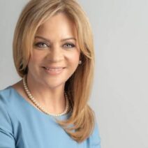 Γυναίκα με ξανθά μαλλιά, γαλάζια μπλούζα και μαργαριταρένιο κολιέ …