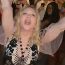 Η Madonna πανηγυρίζει με σηκωμένα χέρια και ανοιχτό στόμα, φορώντας λα…