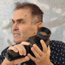 «Ειρήνη - Συνομιλώντας με τον Αριστοφάνη» 1 Κοντινό πλάνο άνδρα με vintage κάμερα Chinon, κοιτάζοντας αριστερά με συγ…