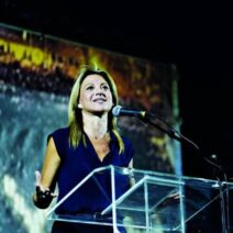 Αχαΐα: Ερχεται για πρώτη φορά εις διπλούν η Μαρία Καρυστιανού – Αποκλειστικές πληροφορίες του Patrapress 1 Η Μαρία Καρυστιάνου μιλάει σε εκδήλωση, πίσω της προβολή.