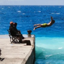Νεαρός πηδάει σε θάλασσα με δύο χρώματα από προβλήτα, με κύματα και…